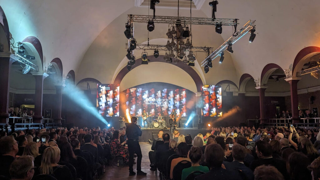 Eine Bühne im Hintergrund, mit 3 großen LED Wänden, davor das Publikum, sowie ein Fotograf der aufnahmen macht. Interkom Mieten in Leipzig, Riedel Bolero Setup , Riedel Intercom